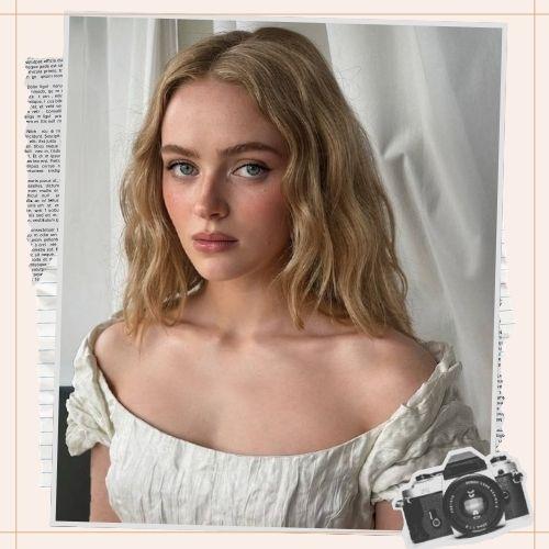 Sadie Sink with wavy blonde hair and center part