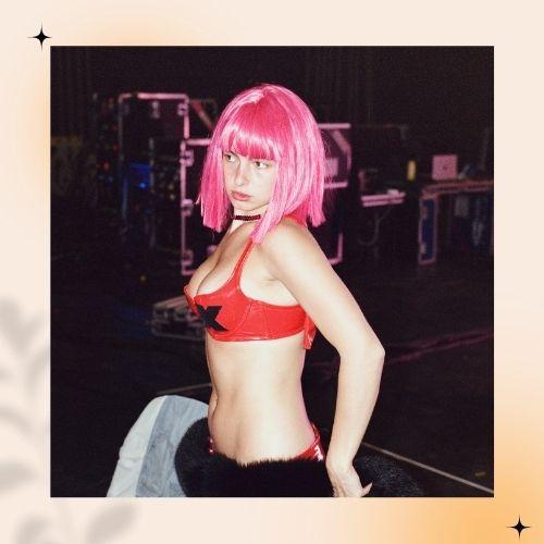 Addison Rae rocking a short, wavy neon pink hair and red bralette