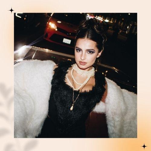 Addison Rae with dark hair styled in an updo bun with white fur coat