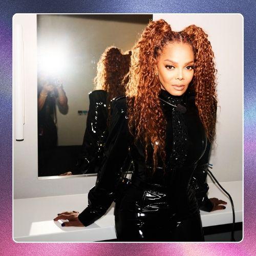 Janet Jackson in a glossy black outfit styled with high curly double pigtails