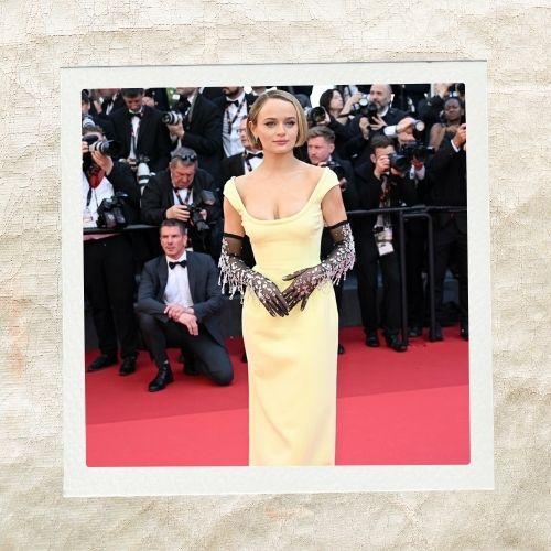 Joey King on the red carpet wearing a yellow dress and gloves with a sleek short pixie haircut