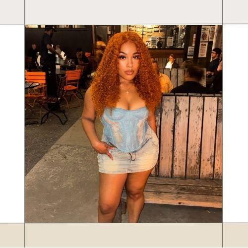 Black woman with long defined auburn curly hair wearing a denim corset top