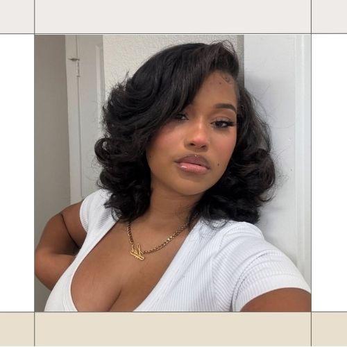Black woman with voluminous shoulder-length dark wavy hair wearing a white top