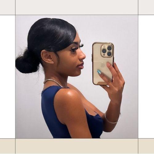 Woman taking a side profile mirror selfie showing a sleek low bun with slicked edges