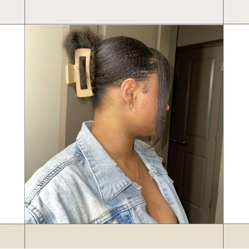 Close-up back view of a woman with black hair styled in a chic claw clip updo wearing a denim jacket