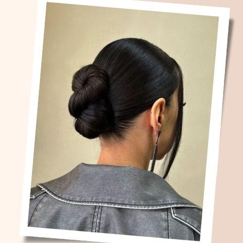 Sleek black hair styled into a low infinity bun with face-framing side strand back view
