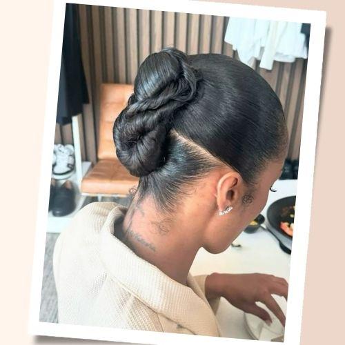 Sleek dark hair twisted into a high infinity bun updo with sharp side parting