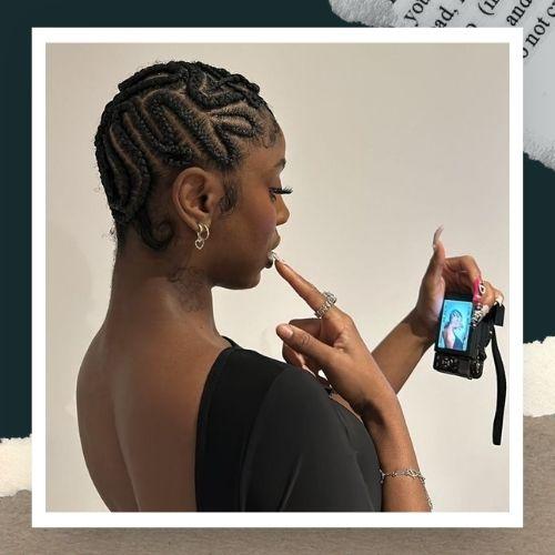 A side profile view of a woman featuring intricate maze-patterned geometric cornrows.
