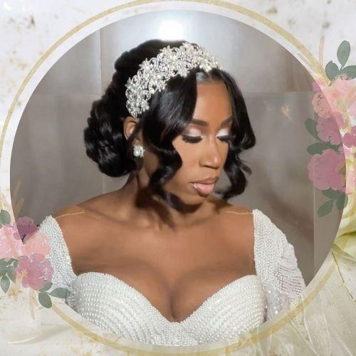 Curly low bun wedding hairstyle for black hair accessorized with a sparkling tiara