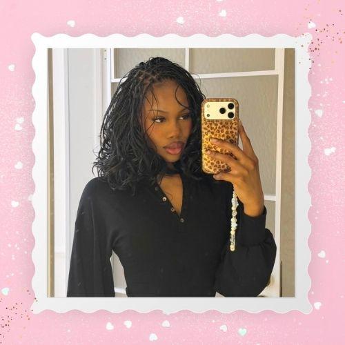 A woman taking a selfie with fine, micro boho bob braids holding a phone.
