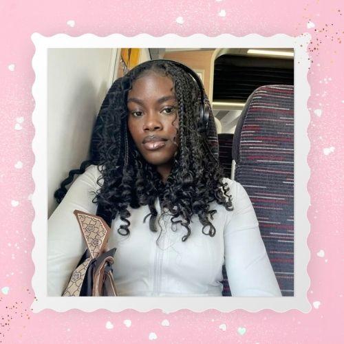 A woman with voluminous loose curls boho bob braids in a white top.