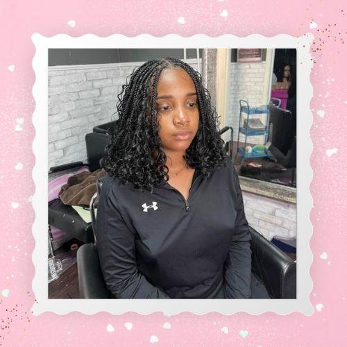 A woman with dark butterfly boho bob braids sitting indoors.