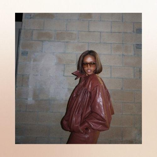 Ryan Destiny with a chestnut brown bob hair cut, wearing a leather jacket.