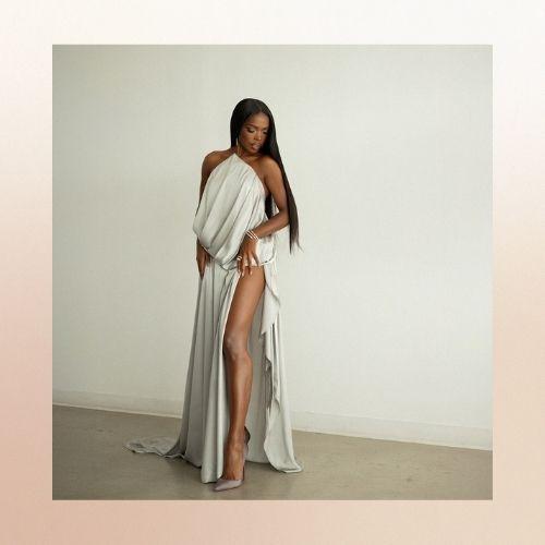 Ryan Destiny with long straight hair, wearing a white high-slit dress.