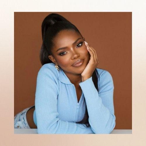 Ryan Destiny styled in a high ponytail, wearing a light blue zip-up top.