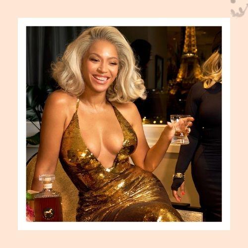 Beyoncé with a high curly pineapple updo hairstyle wearing a light blue turtleneck