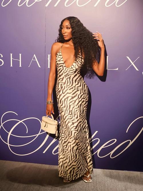 A Black woman wearing a strapless leopard print gown, showing long curly hair glueless lace closure wig.