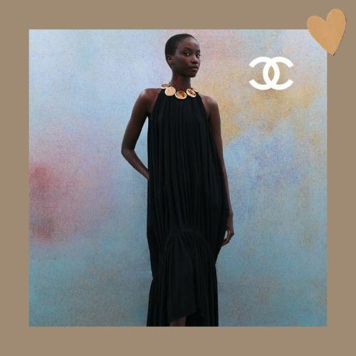 Anok Yai posing with a sleek buzz cut hairstyle in a black gown