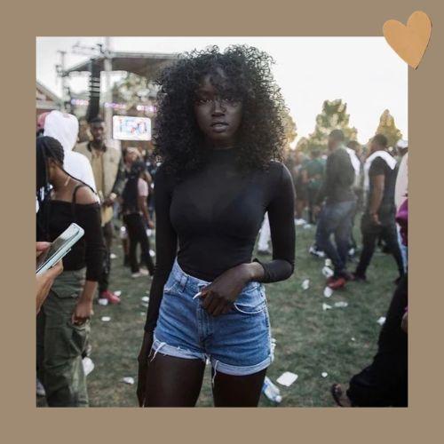 A portrait of Anok Yai showcasing her natural hair at an outdoor gathering.
