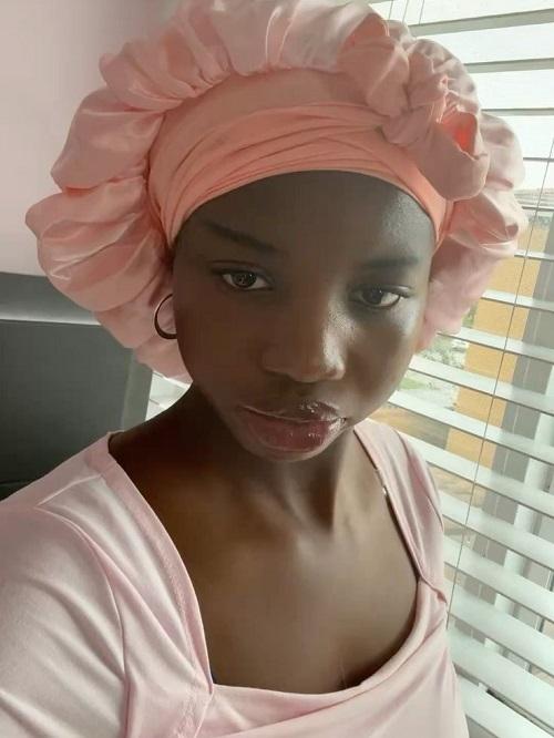 A woman wearing a light pink satin bonnet